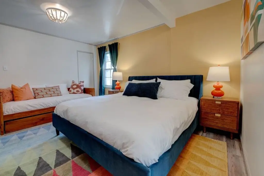 Navy bed with orange lamps, yellow wall