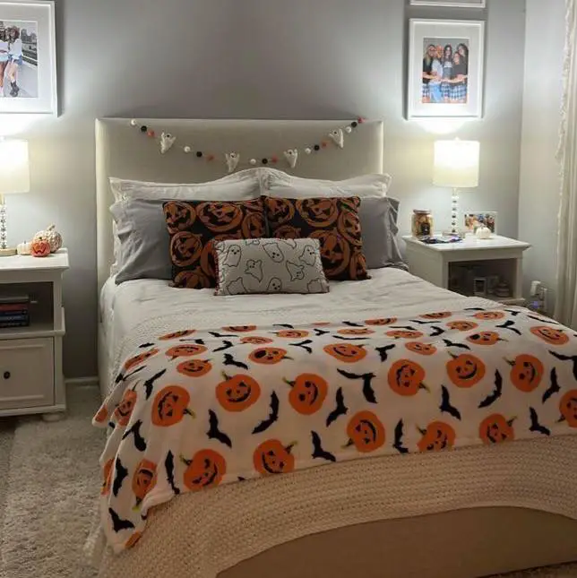 Halloween-themed bedroom with pumpkin-patterned bedding and ghost garland.