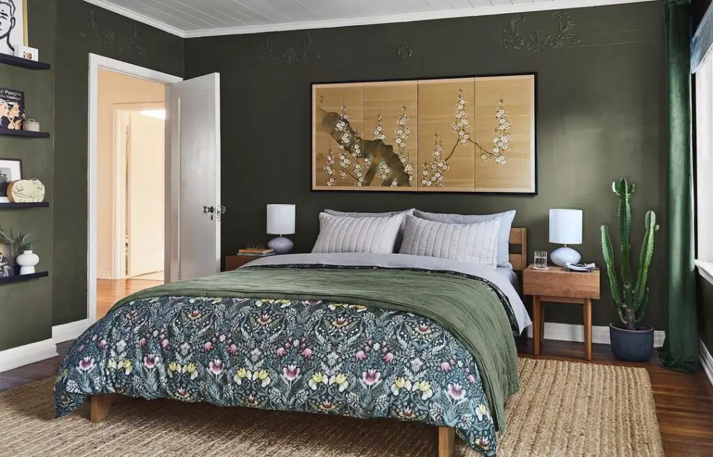 Green bedroom with floral bedding and cherry blossom artwork