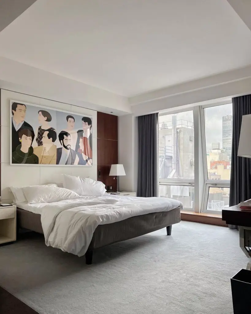 Modern bedroom with city view and large portrait artwork