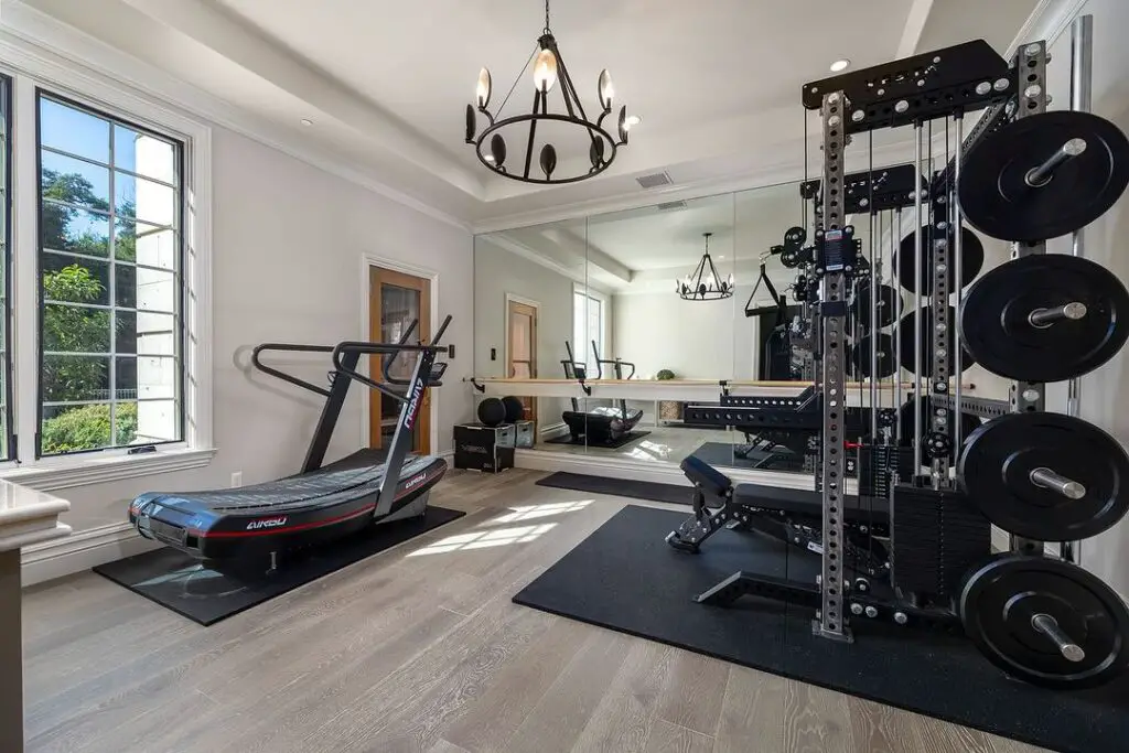 Stylish home gym with chandelier, modern equipment, and large mirror