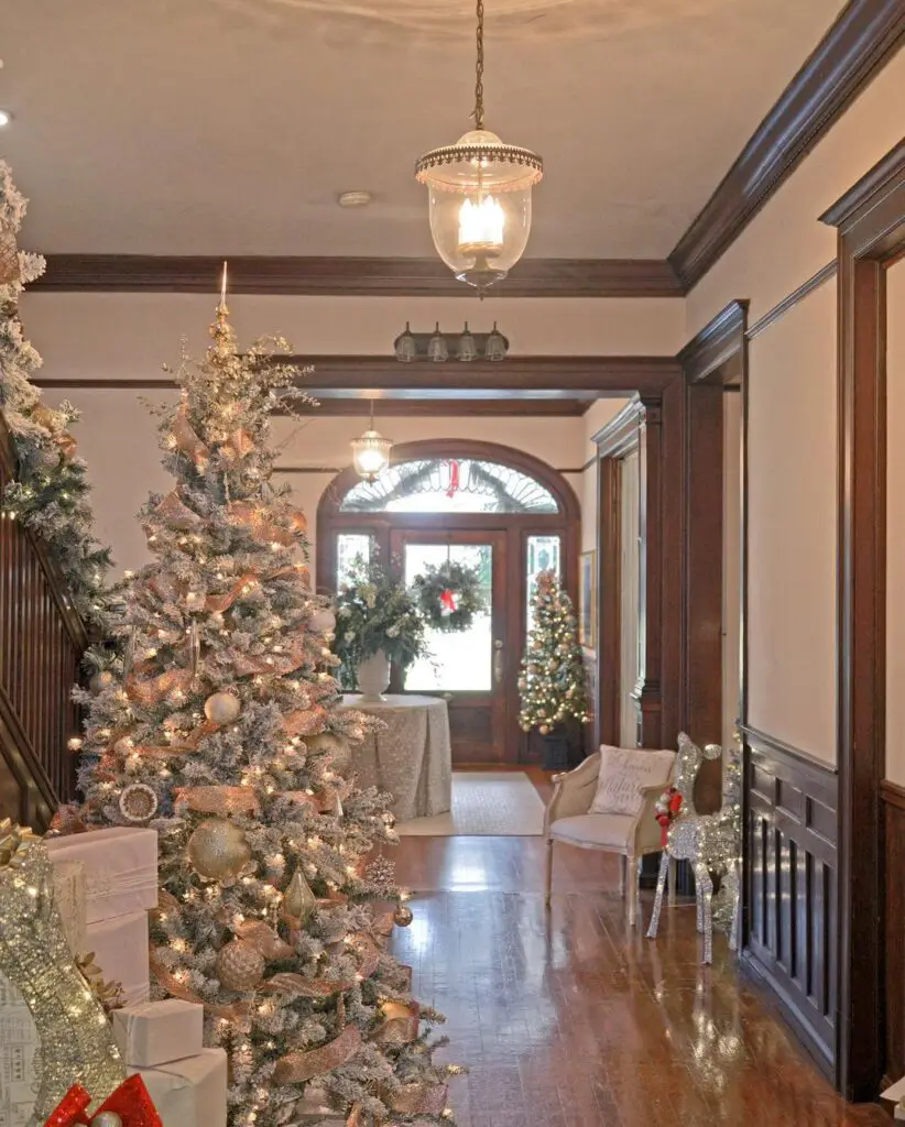 Luxurious foyer with tall metallic Christmas tree and festive decorations.