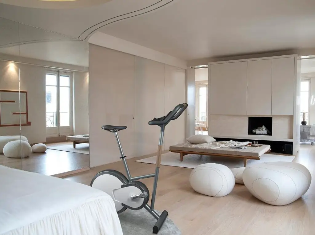 Minimalist living room with exercise bike and white poufs