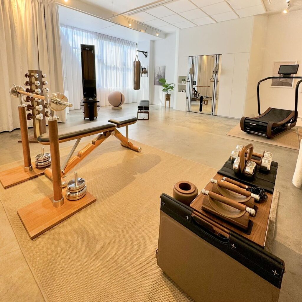 Bright minimalist home gym with wooden equipment and white decor