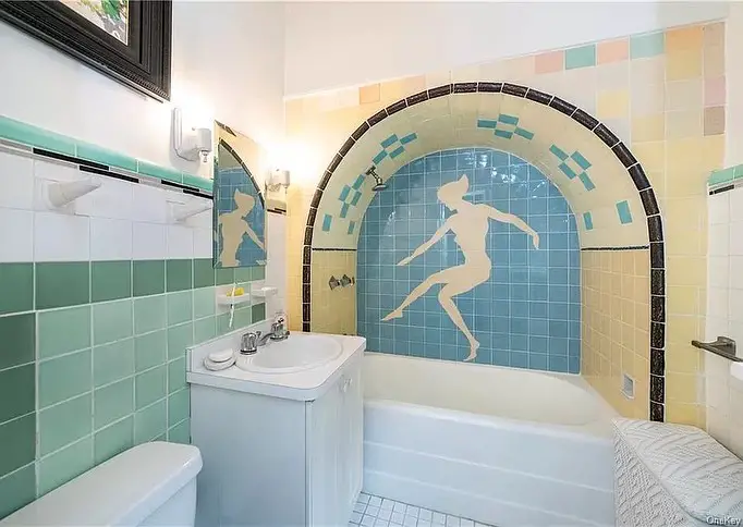 Vintage bathroom with blue tile swimmer mural above tub