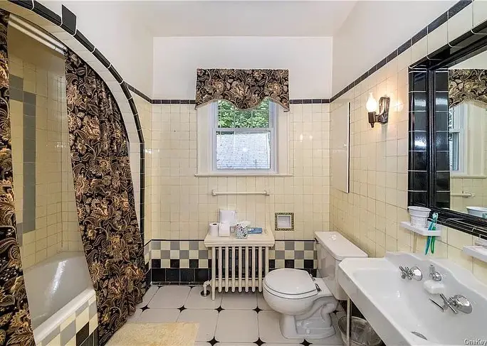 Retro bathroom with black and white tiles and floral curtains