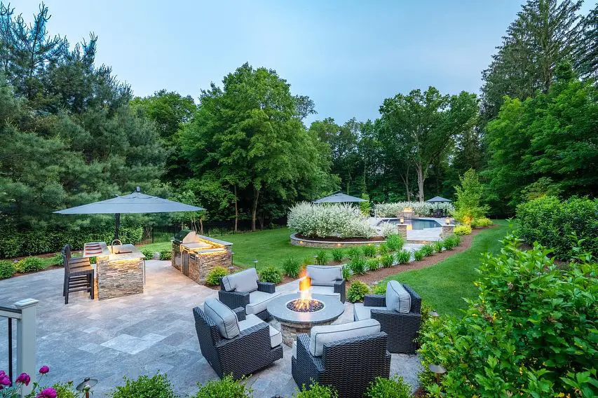 Backyard with fire pit seating outdoor kitchen and distant pool