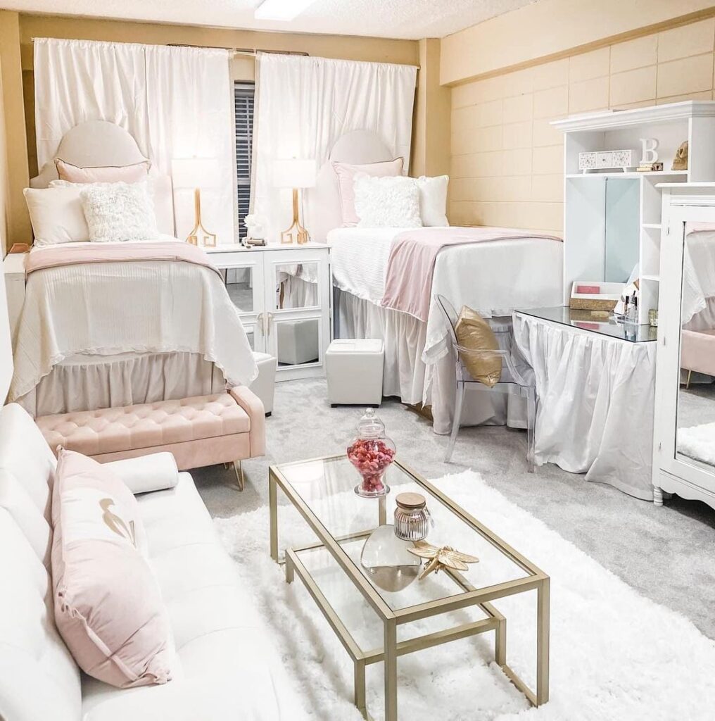 Two twin beds with pink ruffled bedding, mirrored dresser, glass-topped tables