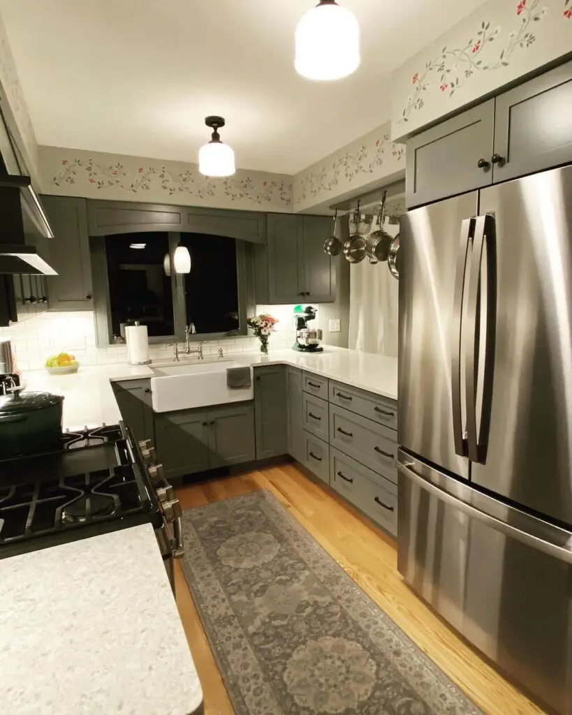 Vintage-inspired kitchen with floral wallpaper, green cabinets, and patterned rug.