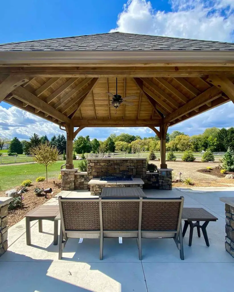 Wooden pavilion with stone bar overlooking expansive landscaped yard