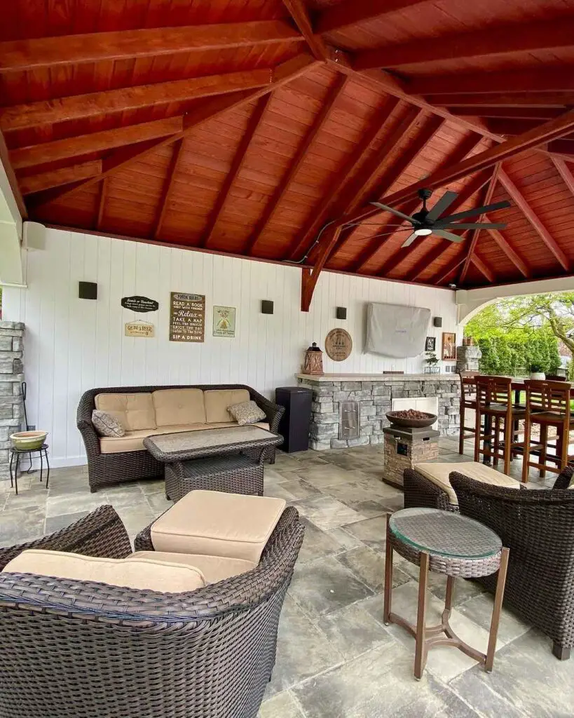 Covered patio with vaulted wood ceiling wicker furniture and outdoor kitchen