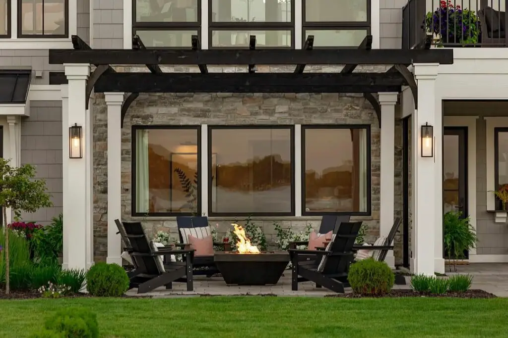 Outdoor patio with fire pit and Adirondack chairs under pergola