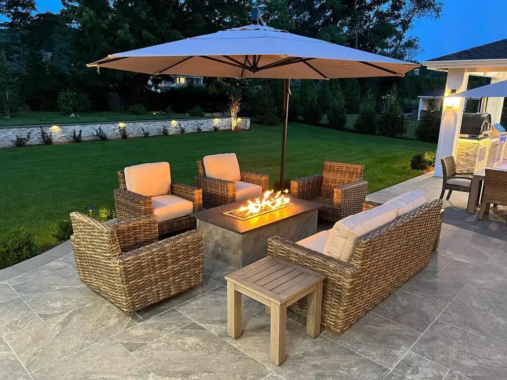 Patio with wicker furniture around fire table under large umbrella
