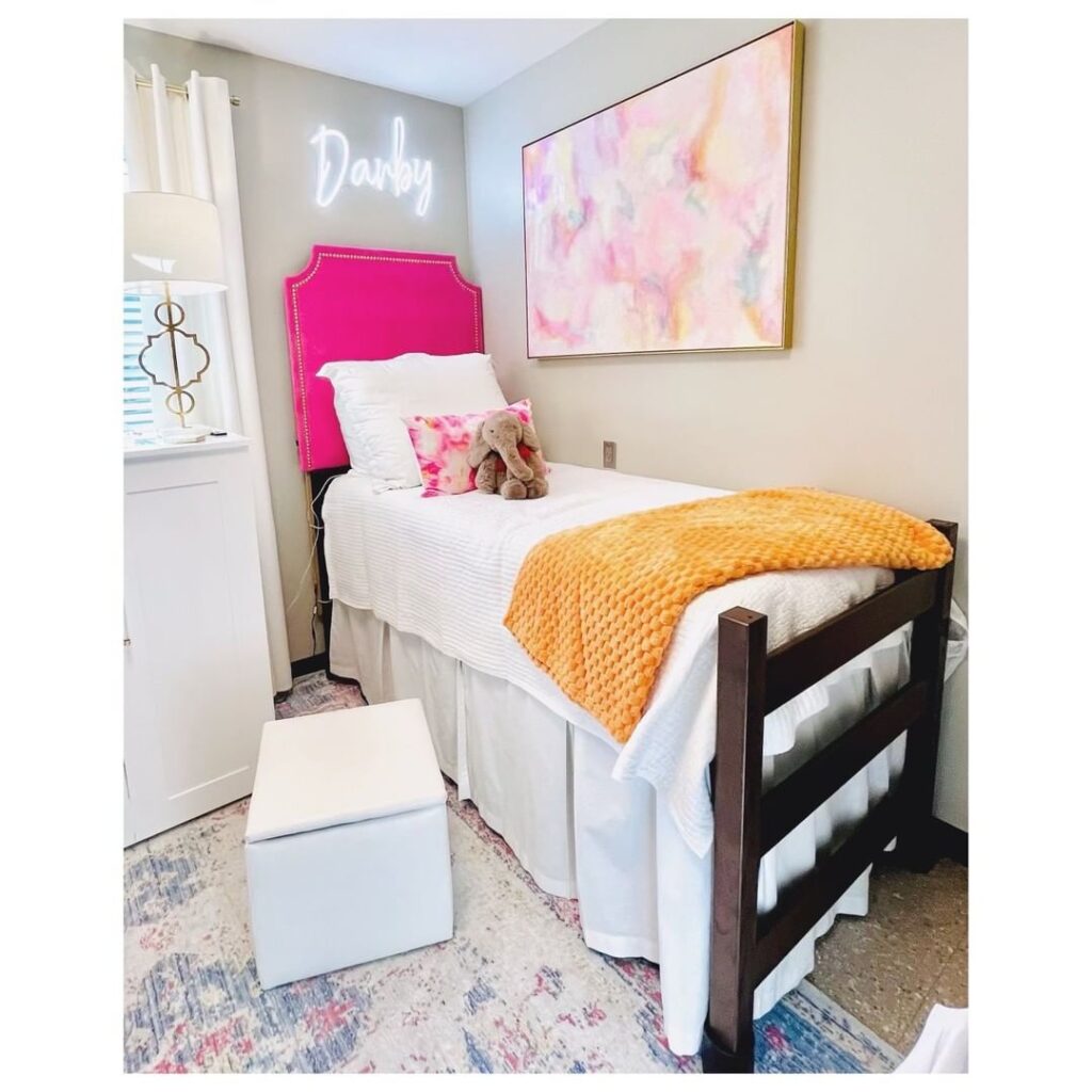 Dorm room with pink headboard neon sign and colorful decor