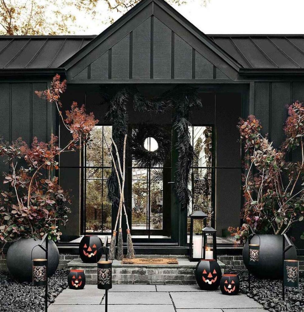 Black house entrance with Halloween decorations and autumn plants