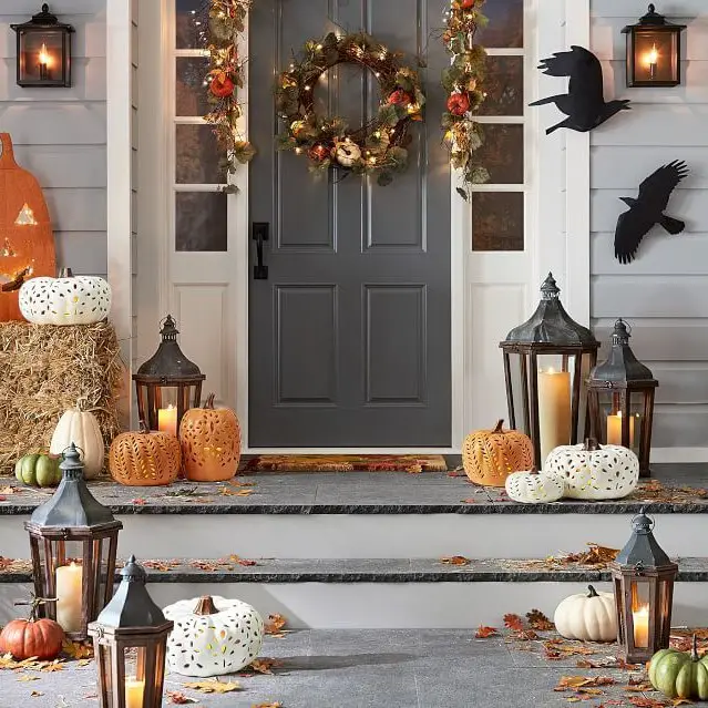 Autumn porch with lit lanterns pumpkins and wreath