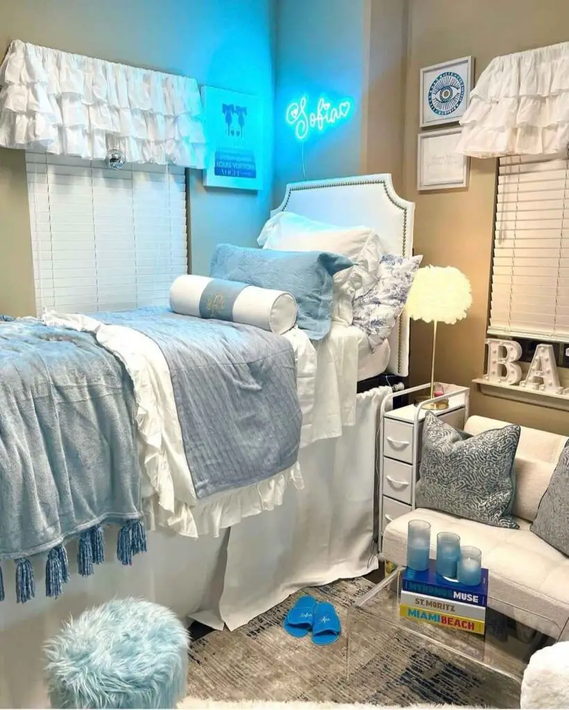 Elegant blue and white dorm room with neon sign and plush bedding.