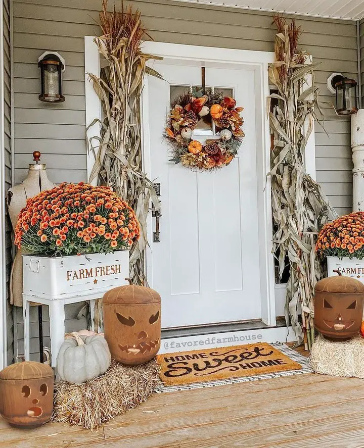 Farmhouse porch with cornstalks mums and pumpkin decorations