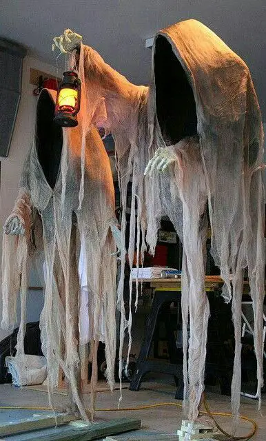 Two tall ghost figures made of draped fabric with lantern