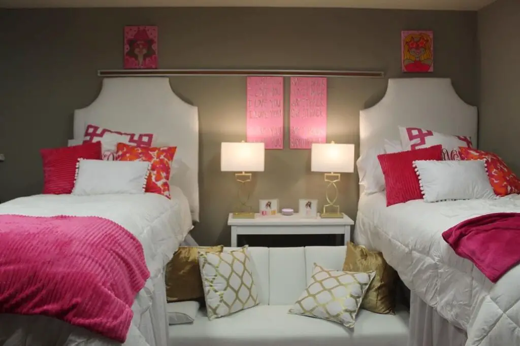 Dorm room with twin beds pink accents and gold decor