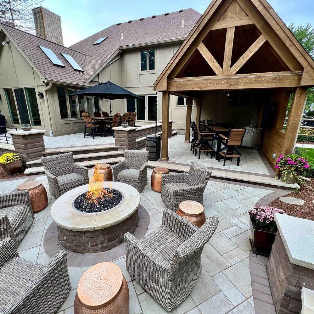 Luxurious backyard patio with fire pit, dining area, and wooden pergola.