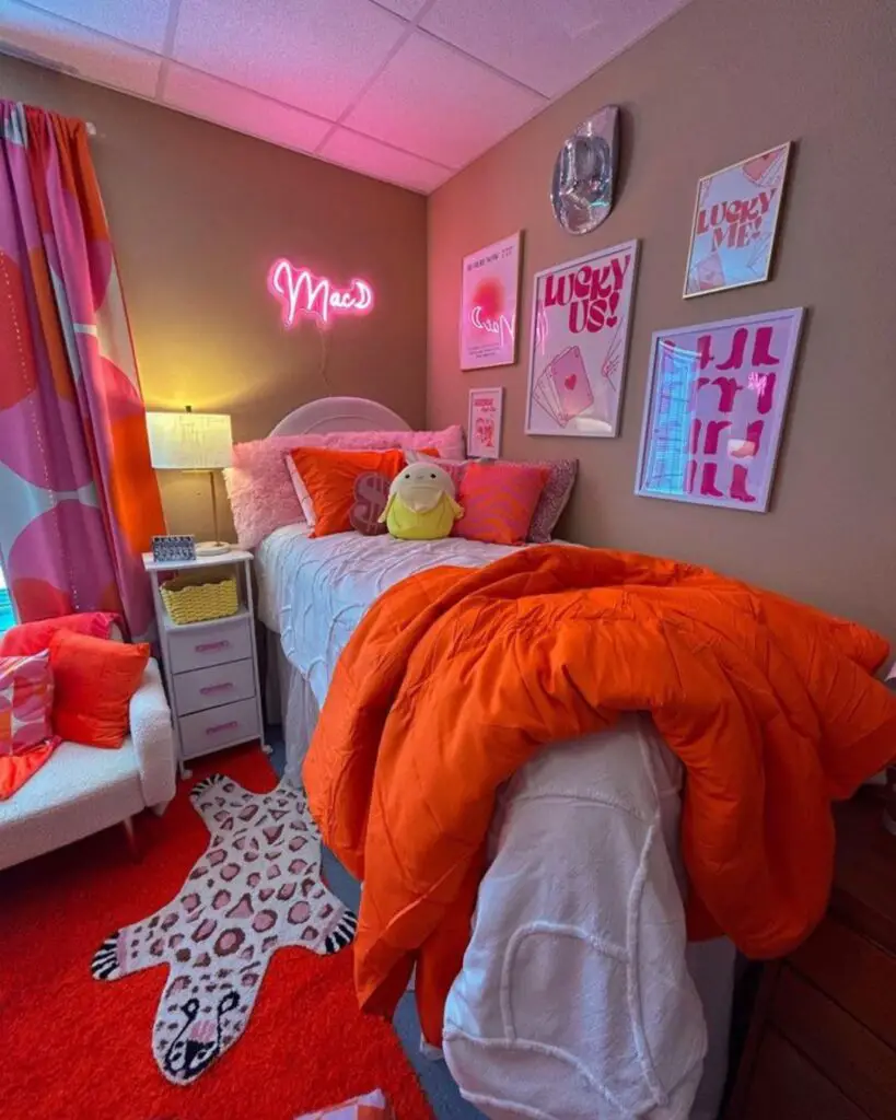 Vibrant pink and orange dorm room with neon sign and quirky decor.
