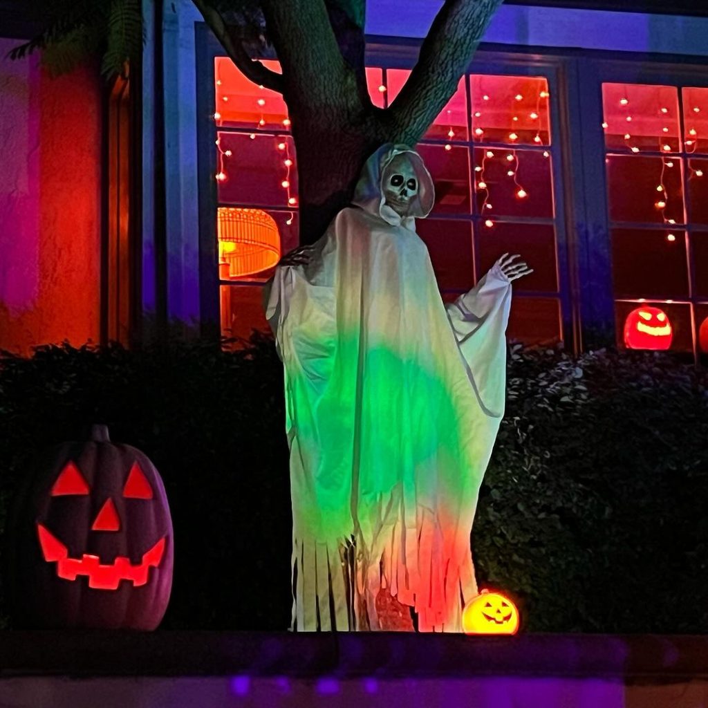 Color-changing ghost decoration with glowing pumpkins and red-lit house windows