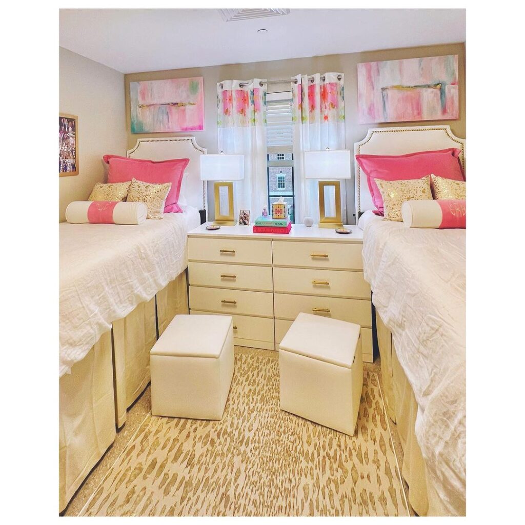 Upholstered twin beds, dresser with ottomans, sheer curtains, artwork.