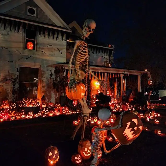 House decorated with giant skeleton and hundreds of lit pumpkins for Halloween