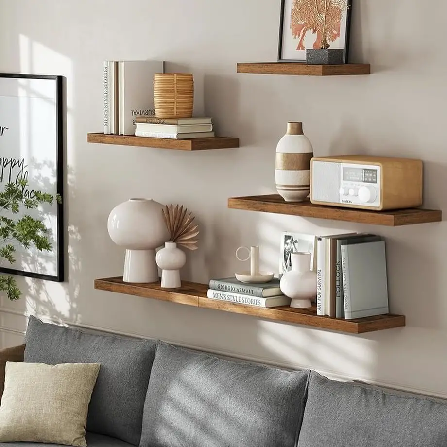 Wooden floating shelves with modern decor above grey sofa