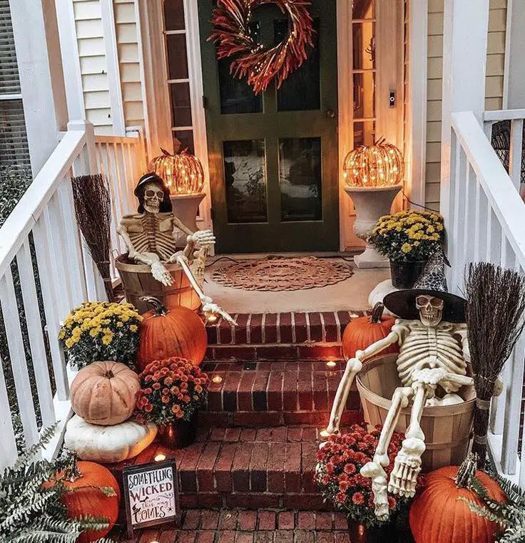 Front porch decorated with skeletons pumpkins and fall flowers for Halloween