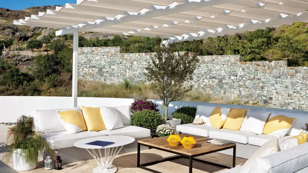 Outdoor seating area with white pergola and stone wall