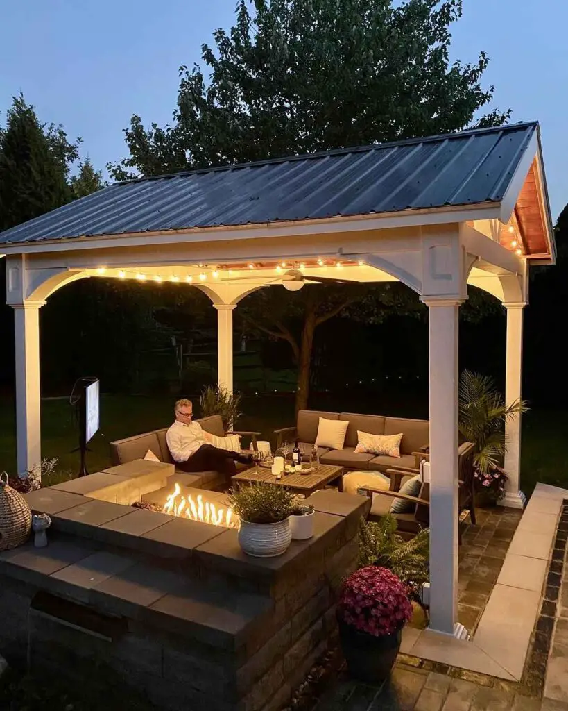 Illuminated outdoor pavilion with fire table and comfortable seating at night