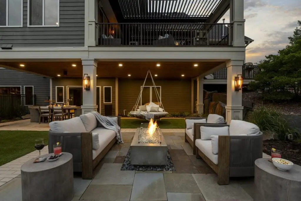 Patio with fire pit sofas and hanging daybed at twilight