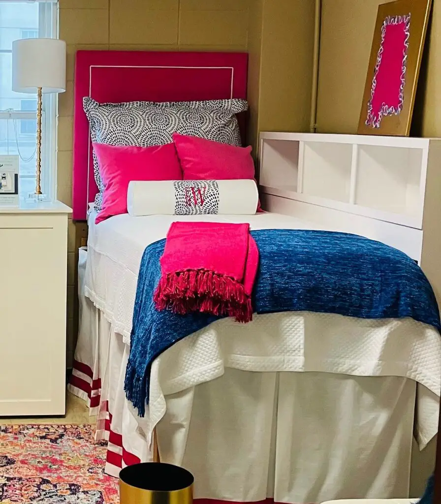 Dorm room with pink headboard navy accents and patterned bedding