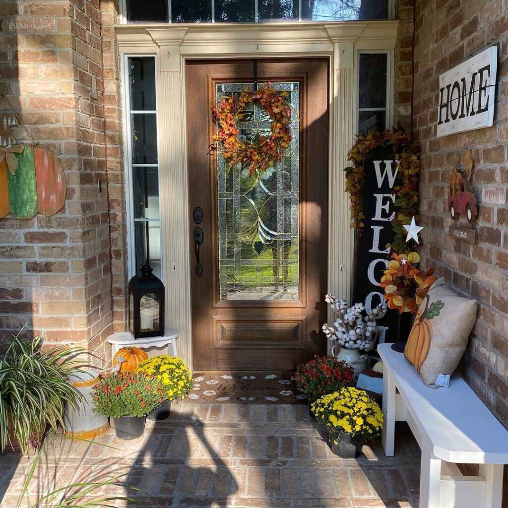 Fall-decorated front door with bench mums and welcome signs