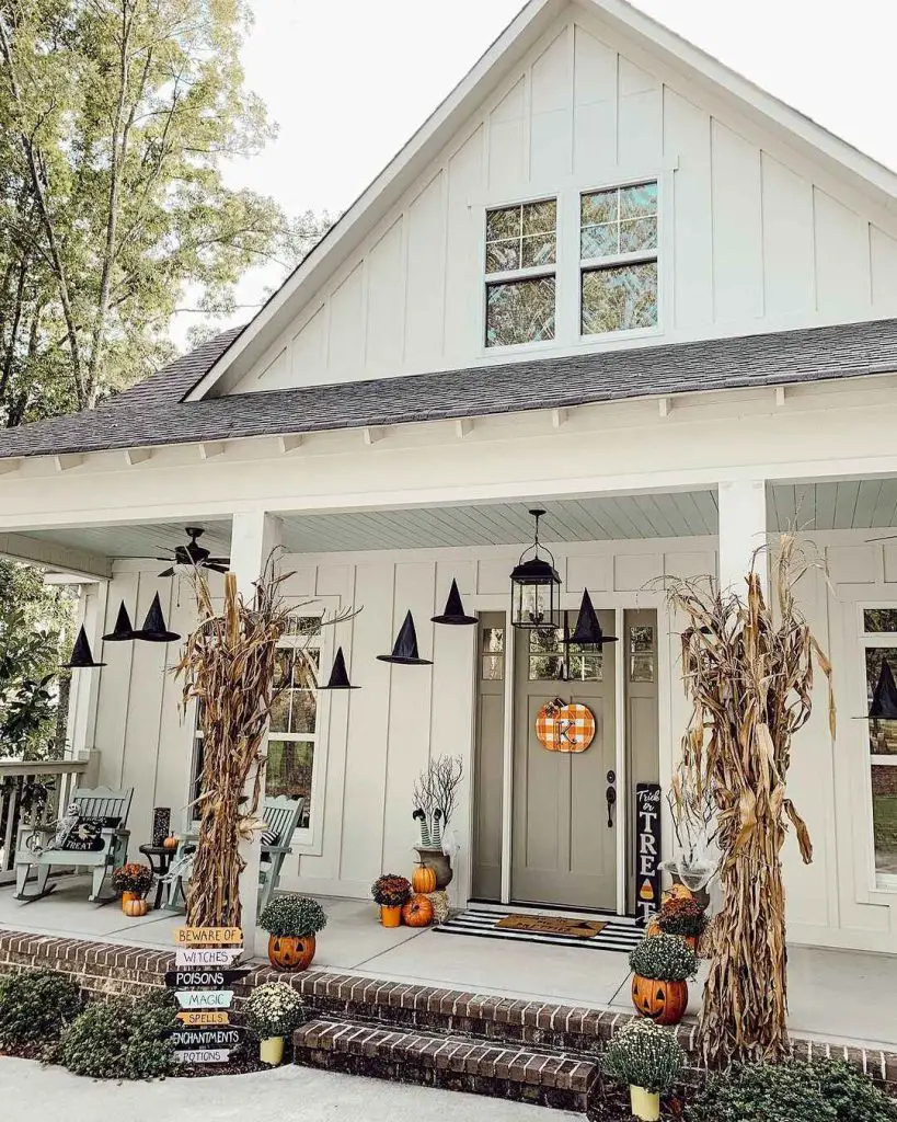 Farmhouse porch decorated with witches hats pumpkins and cornstalks