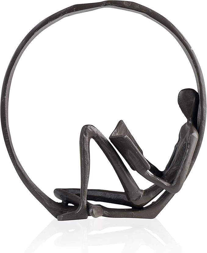 A modern metal sculpture of a person sitting and reading a book.