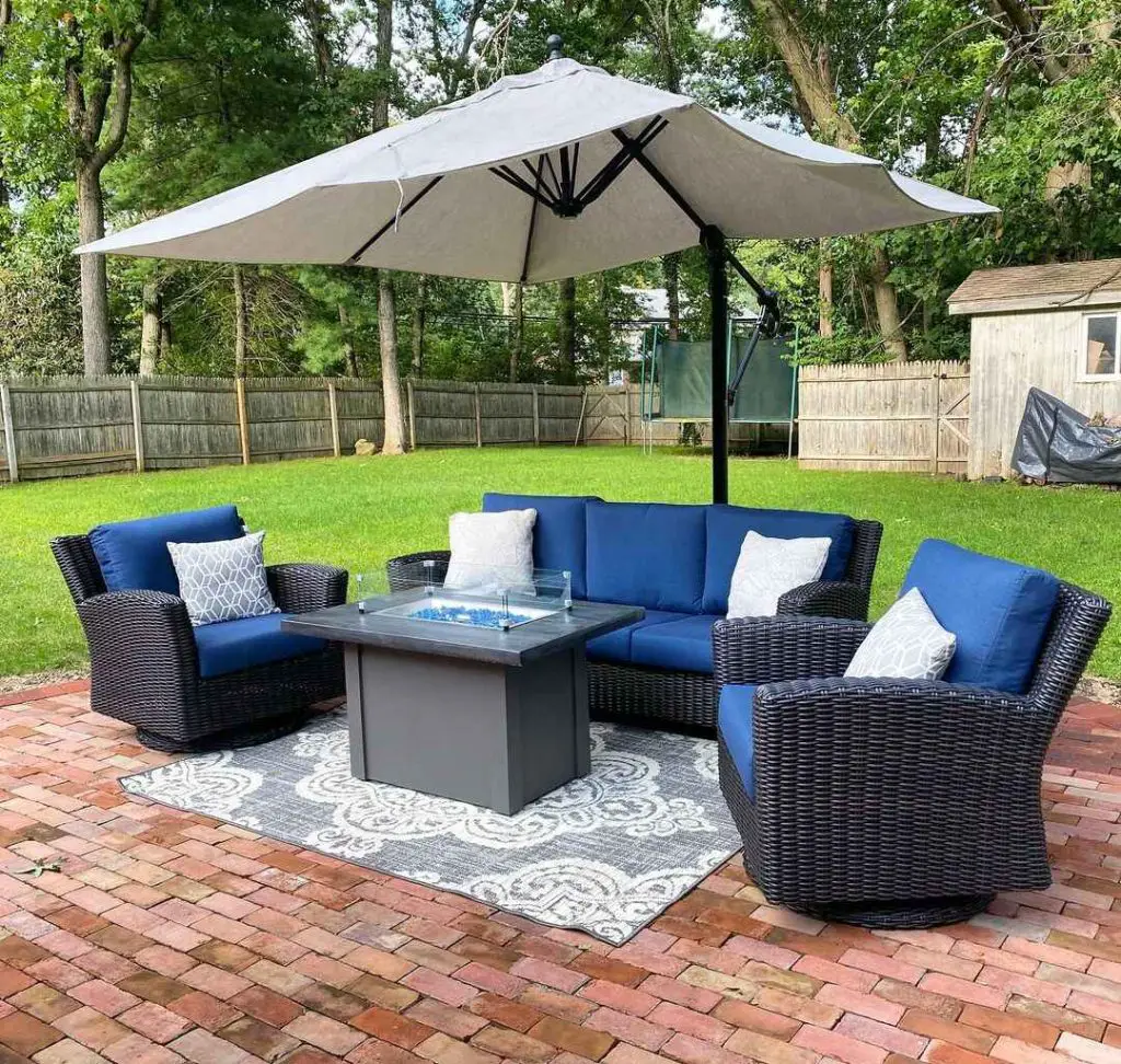 Patio with navy wicker furniture fire table and umbrella