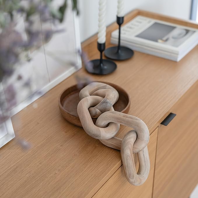 A wooden decorative chain lies in a wooden bowl on a wooden sideboard.