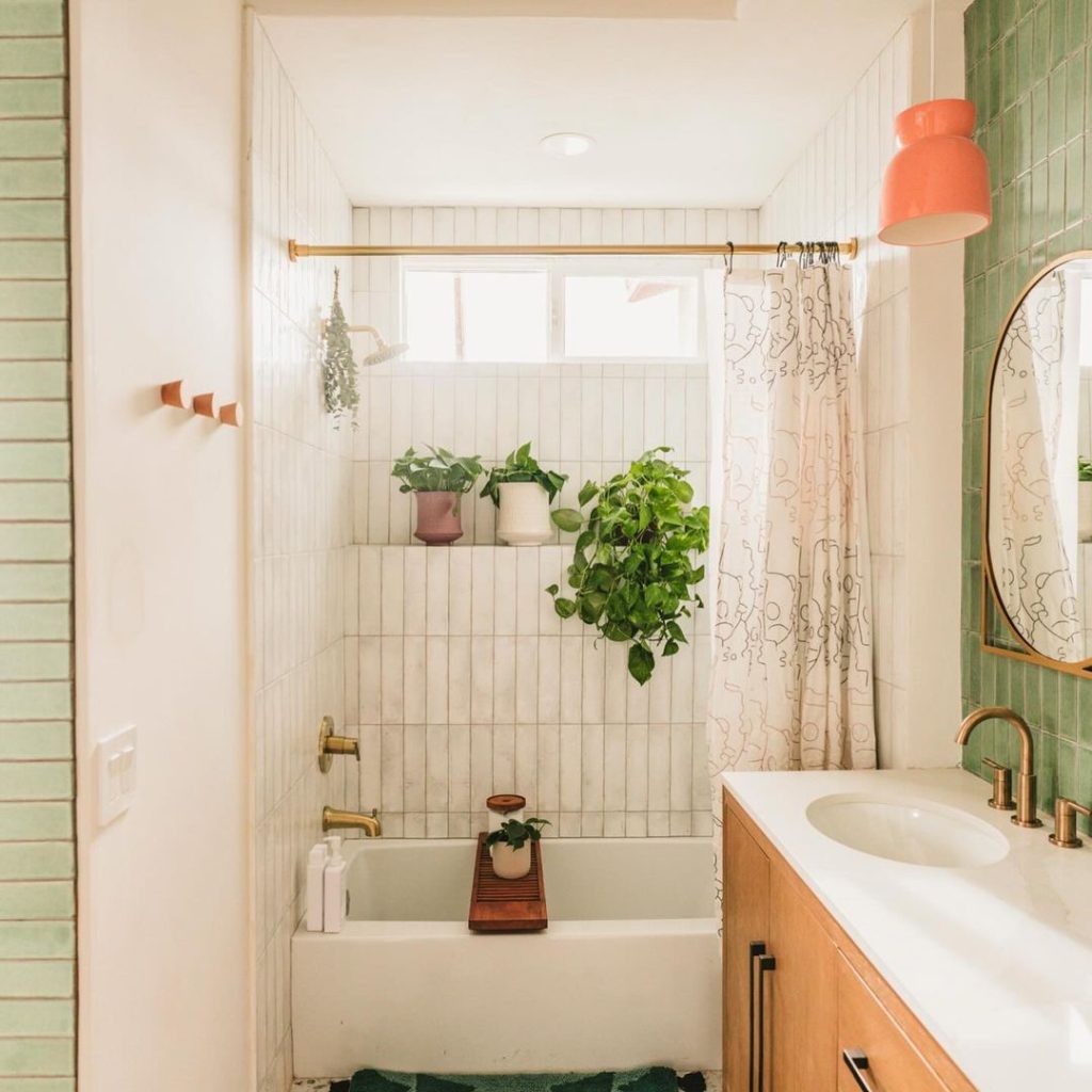 Bright bathroom with plants and green tiles.