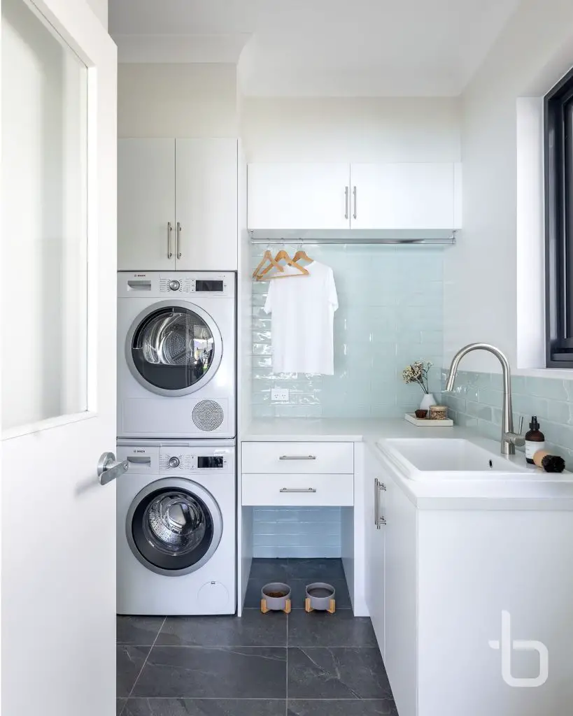 Bright laundry room with blue tiles and stacked machines