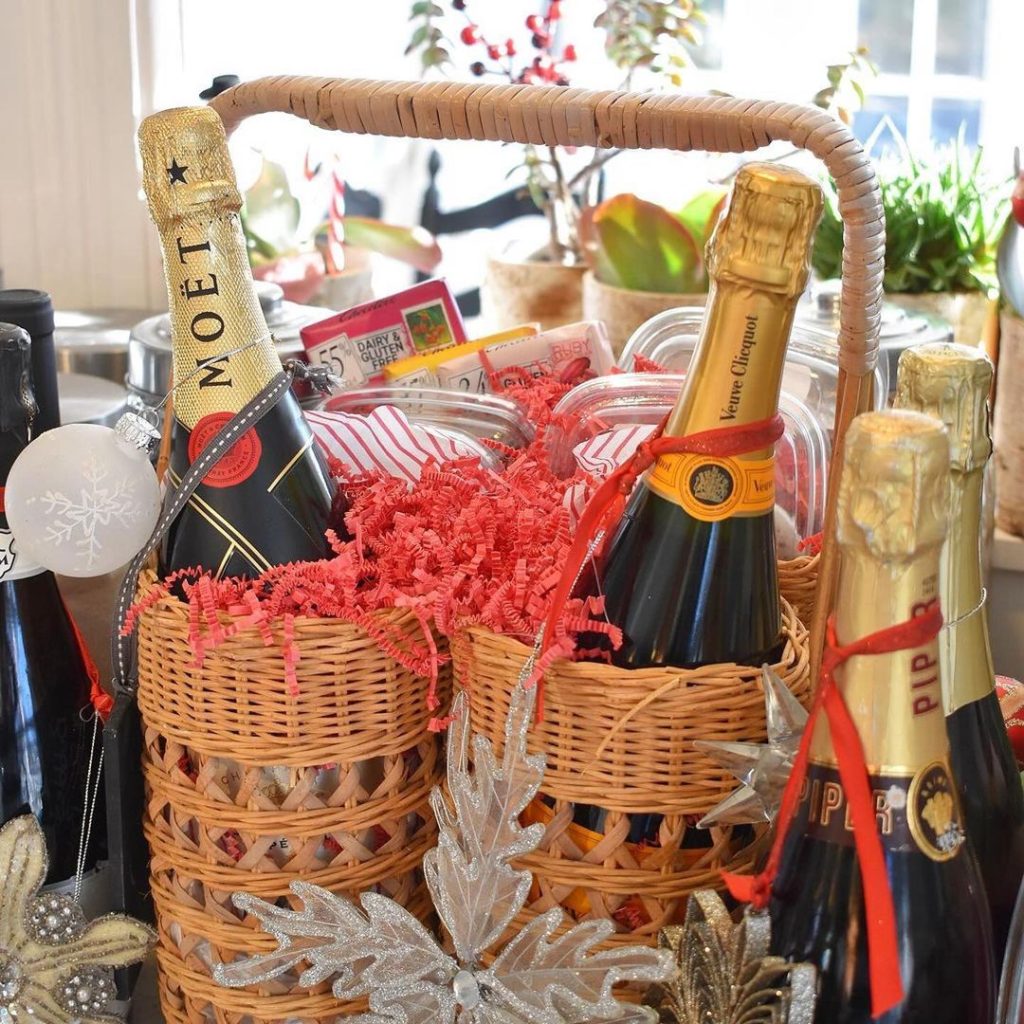 Wicker basket filled with champagne bottles and holiday treats