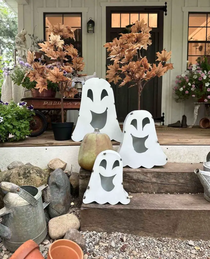 White ghost decorations on porch with fall foliage.