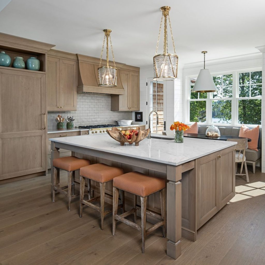 Bright kitchen with wood cabinets, marble island, and glass pendant lights