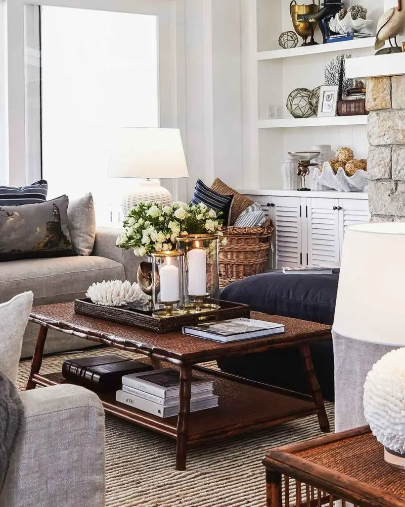 Coastal-style living room with coffee table featuring tray, candles, flowers, and coral decor