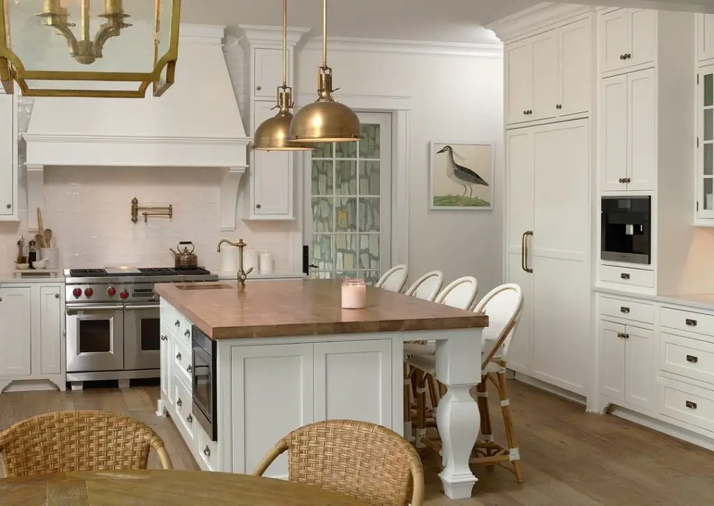 Bright white kitchen with wooden island, brass accents, and coastal-inspired decor