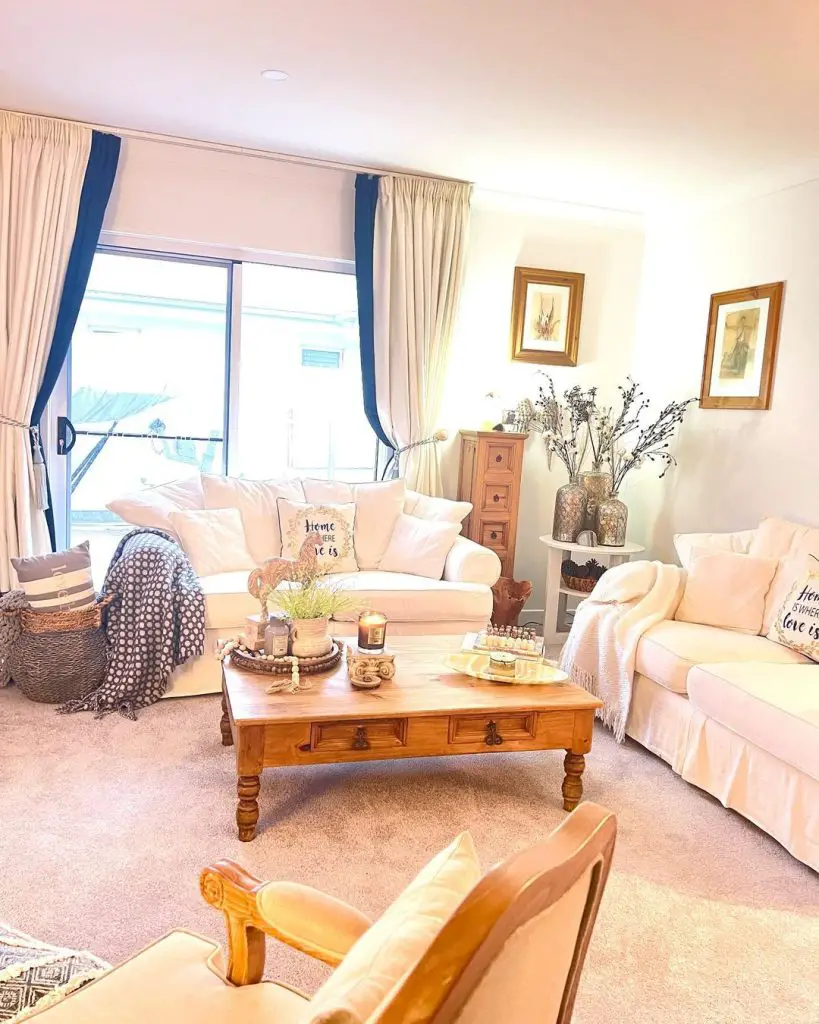Cozy living room with cream sofas, wooden coffee table, and coastal decor.