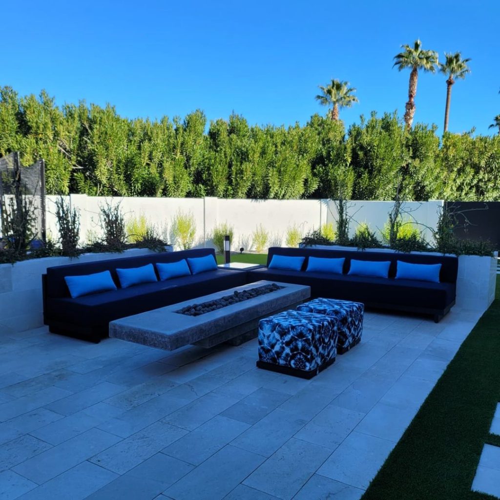 Modern blue outdoor seating area with fire pit and palm trees