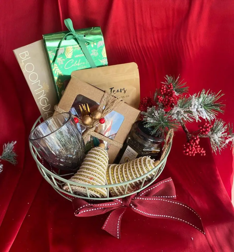Holiday gift basket with books, tea, and festive decorations.